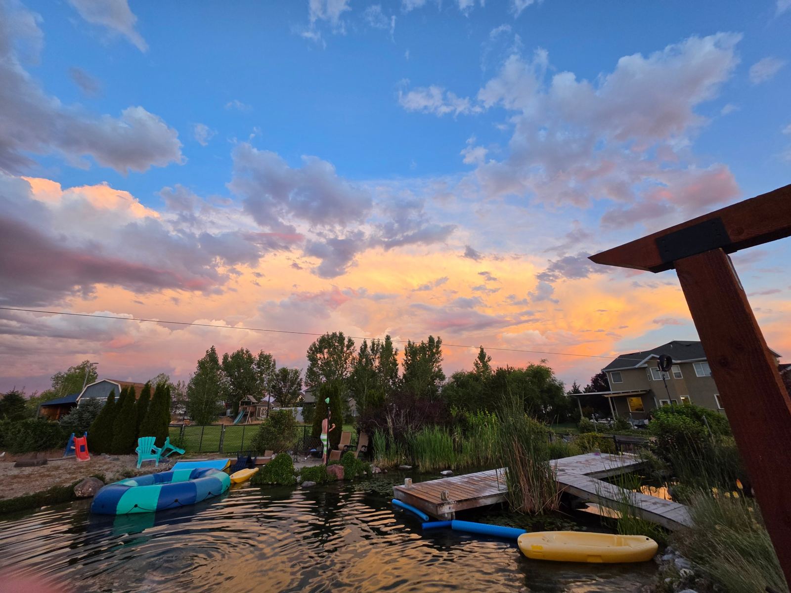 Pool at sunset with dock, floats and evening clouds